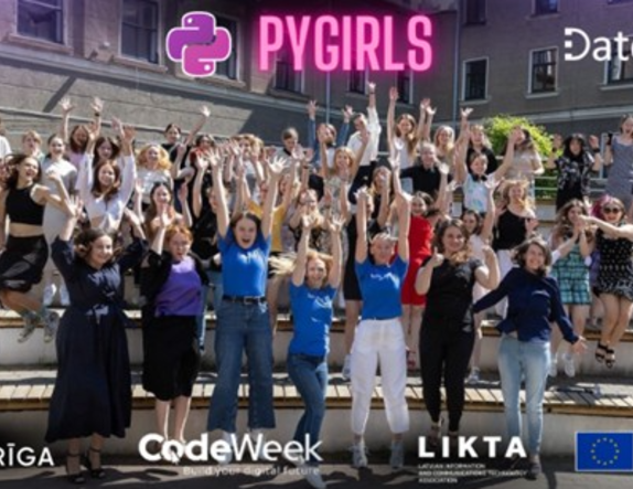 Liela jauniešu grupa pozē uz āra kāpnēm zem uzraksta ‘PYGIRLS’, paceltām rokām atzīmējot programmēšanas apmācību pasākumu.