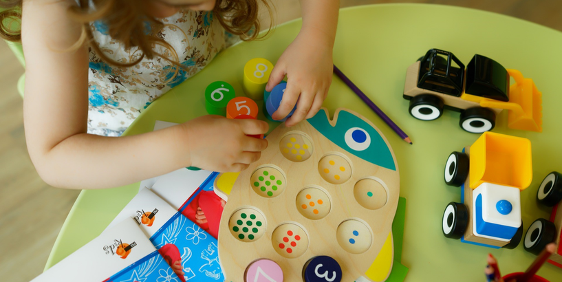 Meitenīte bērnudārzā liek attīstošu spēli