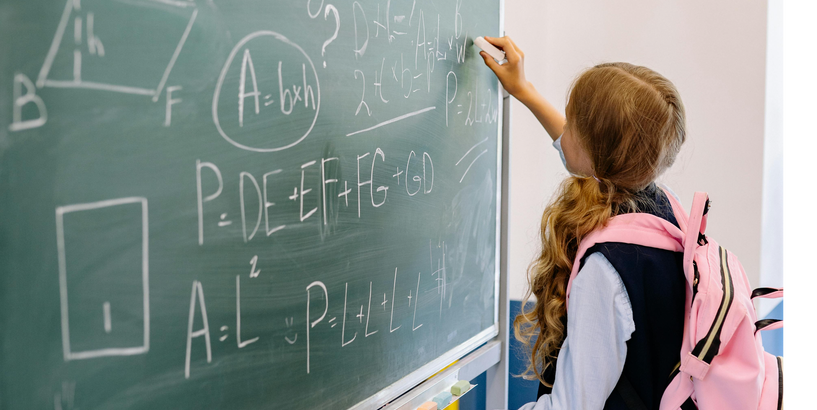 Meitene pie tāfeles risina uzdevumu