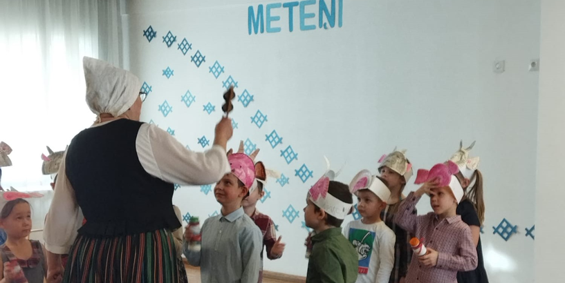 Saimniece kopā ar bērniem ķekatniekiem iet rotaļās